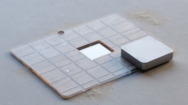 Airy top-down oblique crop of a civic weather-copy table after rain; one smoky transparent acetate weather mask is caref