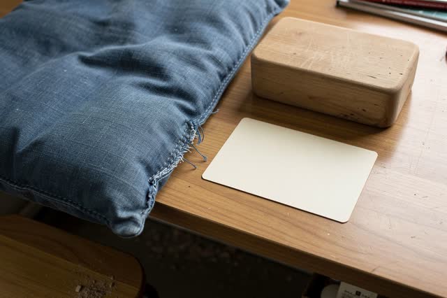 Medium-close process crop on a local museum education table after rain; a faded blue fabric handling cushion is being re