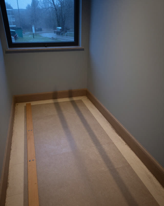 Low wide asymmetric crop of a public stair landing under a covered skylight at early blue hour after rain; a long cool w