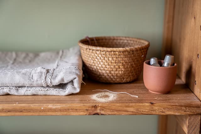 Restful medium-close low crop inside a small neighborhood textile lending room after rain. On a honey-worn wooden shelf,