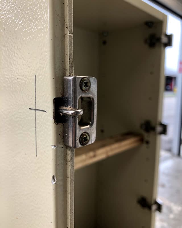 Tight low asymmetric crop inside a public storage cabinet area for folding accessibility ramps after rain, focused on a