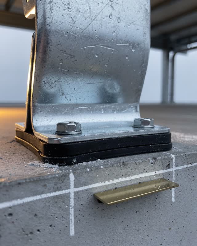 Tight low asymmetric underside crop of a public notice canopy support after rain, focused on a dull galvanized steel bra
