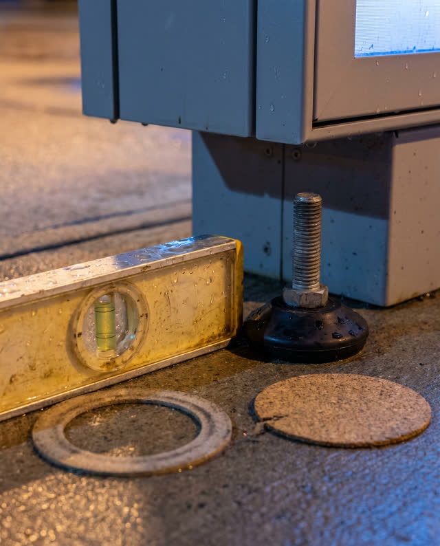 Tight low asymmetric crop during maintenance of a public display case after rain, focused on a small scratched spirit le