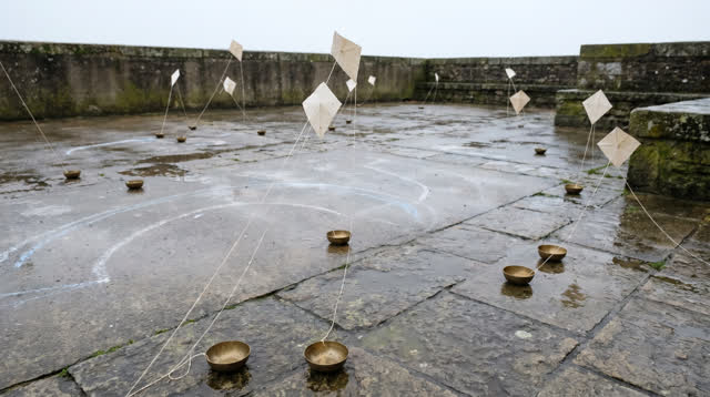 An open civic courtyard after rain, low walls and wet pavement under bright diffuse noon light. Blank paper weather tags