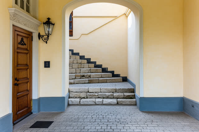 A narrow back stair landing in an old civic building after rain has passed, framed low and horizontally with generous qu