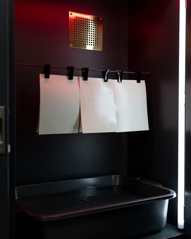 A community darkroom drying corner after a workshop, empty of people, with no visible photographs and no readable labels