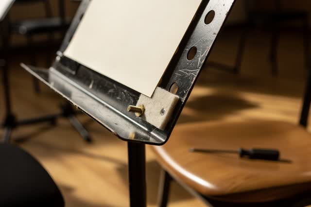 A small community music room after rehearsal, empty of people, with chairs mostly cropped away and no readable sheet mus