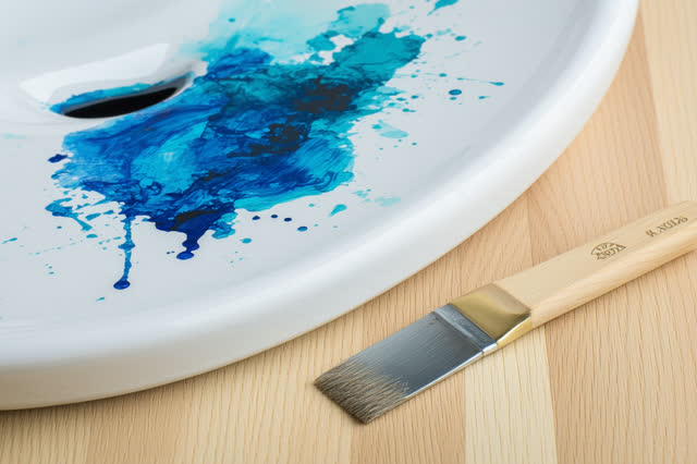A small public art classroom sink bench after a watercolor lesson, clean but visibly used. A loosened white ceramic rins