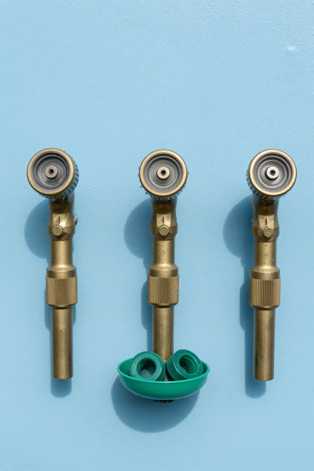 A bright community garden tool board cropped close, with no signage or readable labels. Three clearly identifiable brass