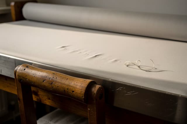 A small laundry pressing corner after clean linens have been removed, empty of people, with no bakery cooling rack, drin