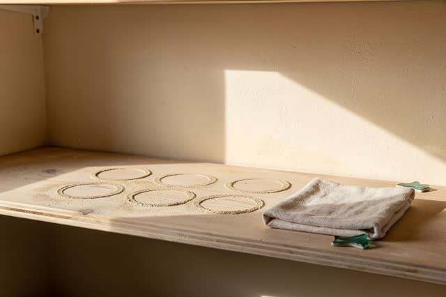 A small pottery studio drying alcove after finished cups have been carried away, empty of people, with no glaze-test til