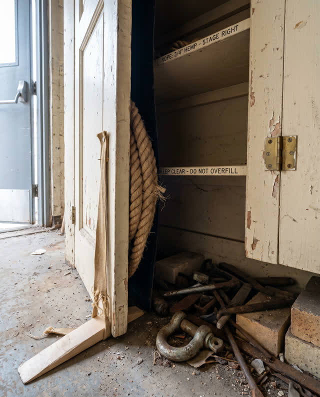 A small theater rope cabinet without pulleys, empty of people, with no pulleys, readable labels, stage props, apocalypti
