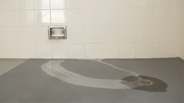 A public washroom service wall after morning cleaning, empty of people, with no readable labels, mirrors, graffiti, stat