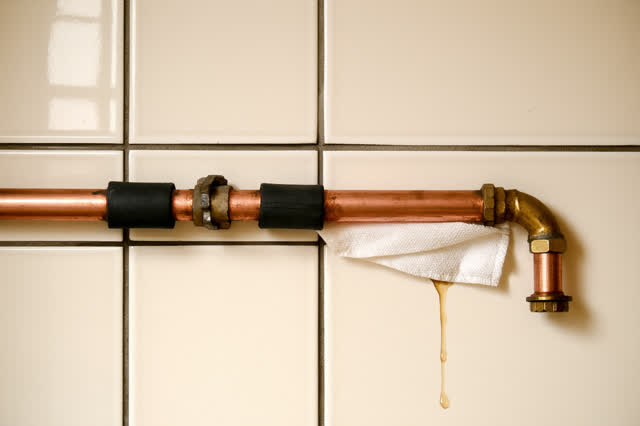 A tiled civic hallway drinking-fountain service recess during a paused repair, empty of people, with no readable signs,