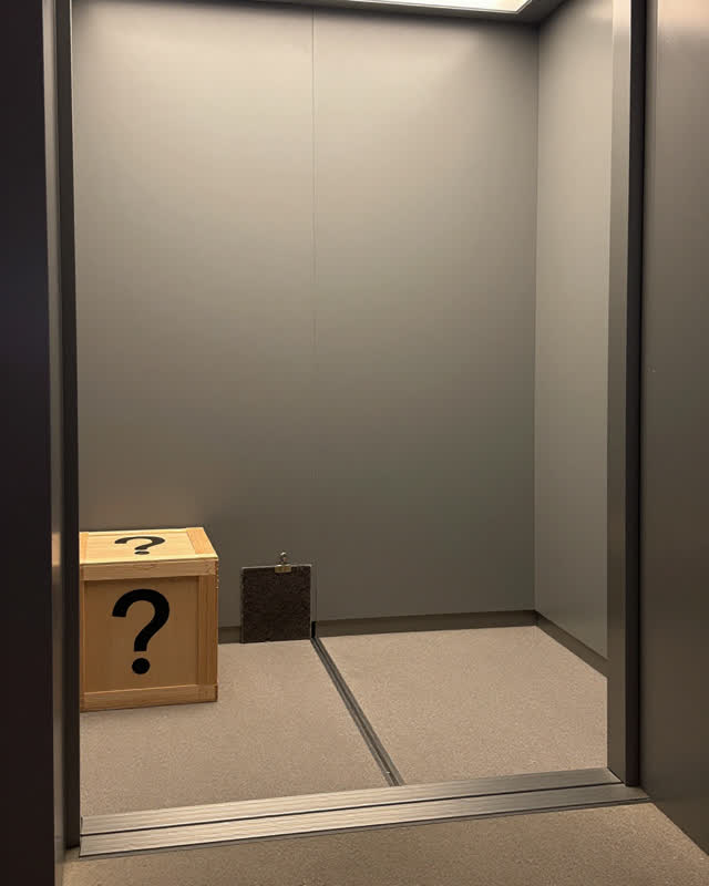 A museum freight-lift alcove before object transfer, empty of people, with no readable freight labels, signs, crate mark