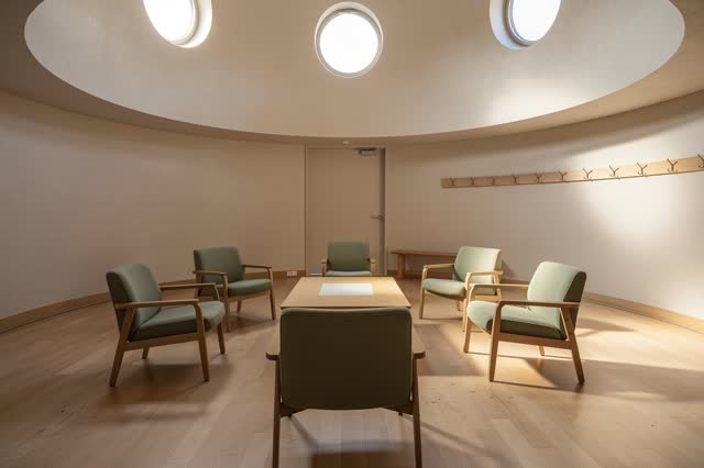 A small public waiting rotunda after morning use, empty of people, with no readable notices, lost-and-found hooks, melan