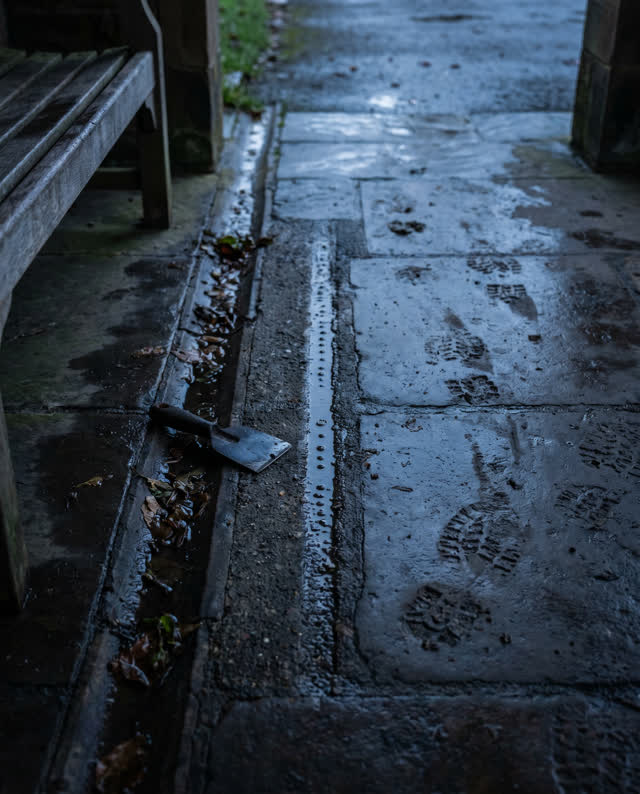 A public weather porch after rain, empty of people, with no readable signs, doorway-threshold focus, flood catastrophe,