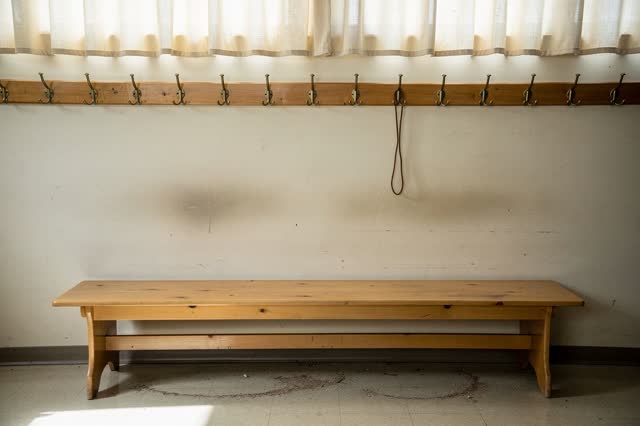 A community hall cloakroom bench after an event has ended, empty of people, with no readable notices, library carts, los