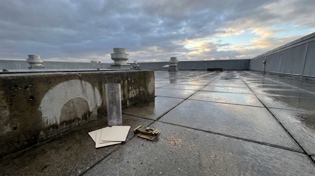 A civic building rooftop weather corner after rain, empty of people, with no readable labels, storm drama, weather-stati