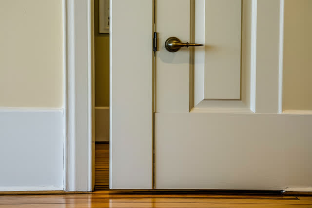 A community meeting-room threshold with a heavy interior door propped gently open, empty of people, with no readable sig