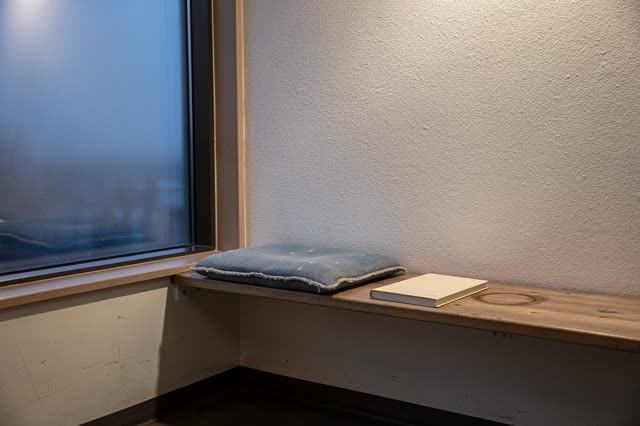 A small public reading nook after closing, empty of people, with no readable writing, tea shelf repetition, piano corner