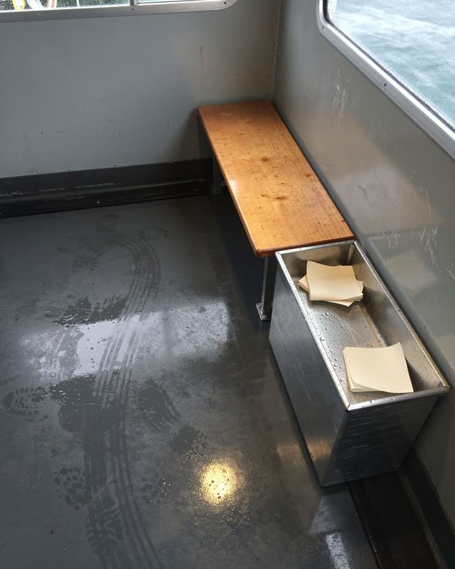 A ferry-adjacent waiting vestibule after rain, without maps, route tables, ropes, or ticket signage, empty of people, wi