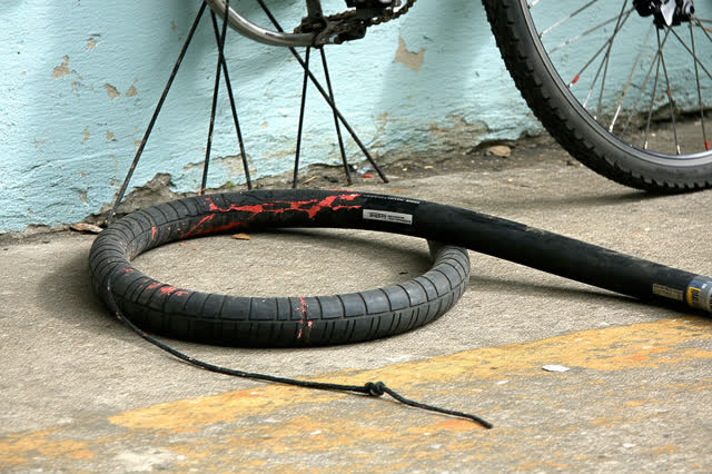 A community bicycle repair alcove beside a public path during a small pump repair, empty of people, with no readable sig