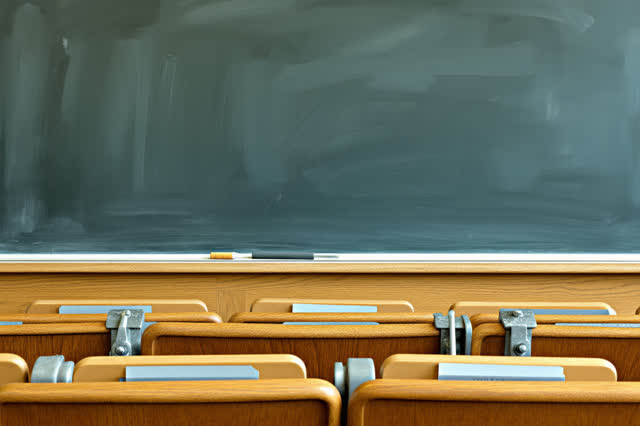 An old lecture hall front wall during a chalkboard edge repair, empty of people, with no readable formulas or text, no r