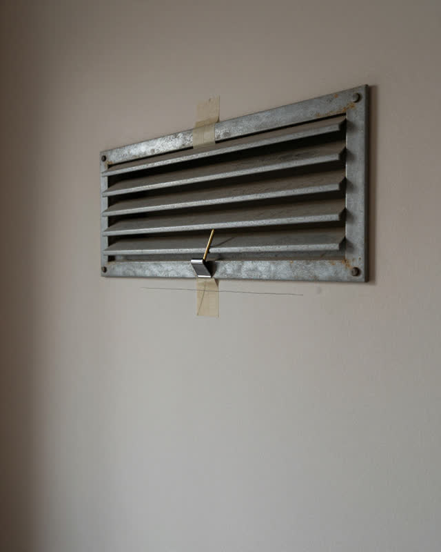 A civic meeting-room upper wall with an old ventilation register, empty of people, with no readable signs, no floor obst