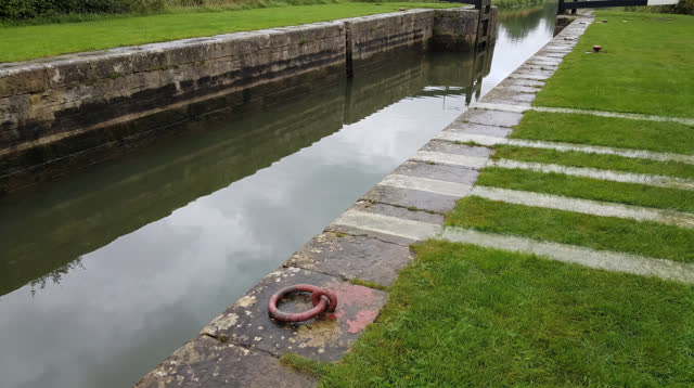 A buoyant dream on a canal lock lawn after rain: old water marks on limestone walls seem to rise into pale reflections a