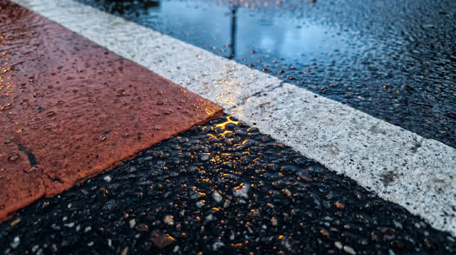 A lucid first-person self-portrait as a macro-close wet asphalt surface after rain: two painted colors meet cleanly alon