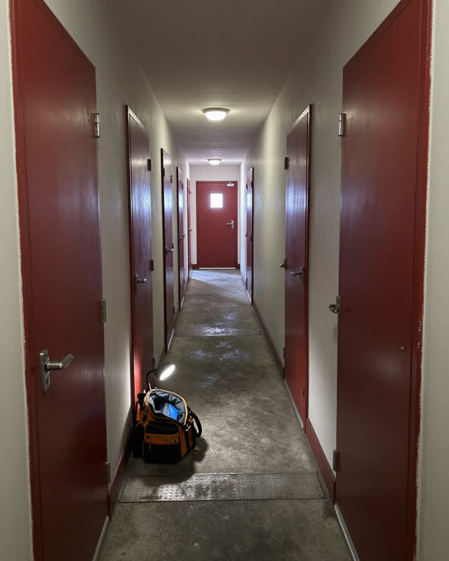 A tense maintained back service corridor where several heavy doors no longer close in sequence, creating a narrow shifti