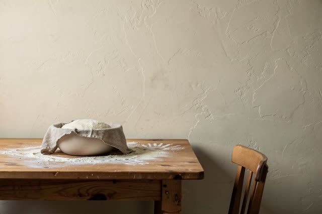A serene quiet image in a small bakery preparation room between shifts: one matte ceramic bowl of rising dough rests ben