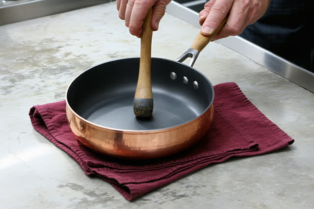 An intimate repair in a closed diner prep room before evening service. Show one cook's hands setting a new copper rivet
