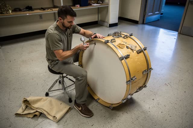 I dream of a percussion technician seated beside a large school bass drum, replacing its torn head with a new cream memb