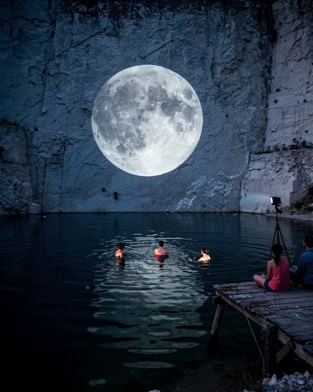I dream of an old quarry swimming hole at blue hour during a small outdoor film. A simple monochrome image of the moon i