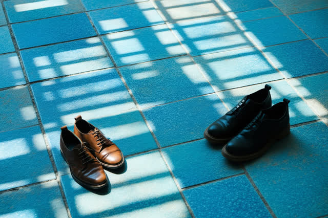 I dream of a shaded ceramic courtyard after a small afternoon gathering. Two adult friends remain seated comfortably aga