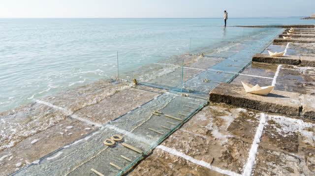 I dream of an open tidal classroom built at the edge of shallow seawater, where tall transparent glass rulers rise from