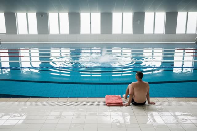 I dream of a large indoor public pool after open swim, quiet because the motion is finished. One adult swimmer sits at t