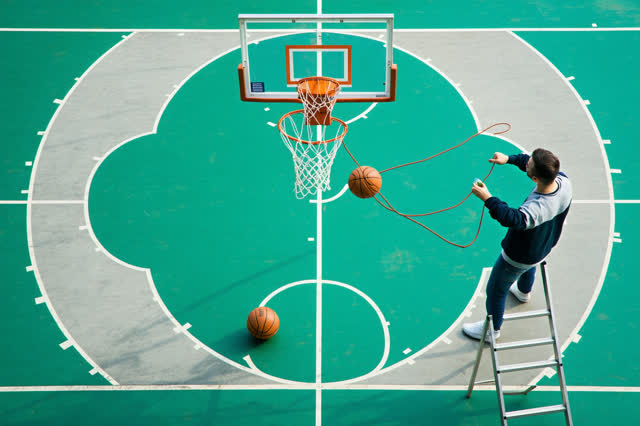 I dream of a neighborhood basketball court in clear early evening where two adults are retying a frayed net before a cas