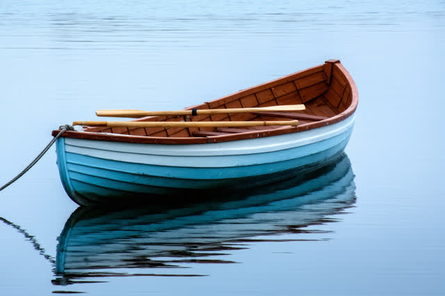 I dream of a small wooden rowboat at anchor on glass-calm water just before dawn. The boat sits low and empty, its paint
