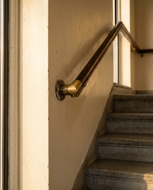 I dream of a municipal stairwell landing where a brass handrail bracket has loosened over decades of use, so the rail no