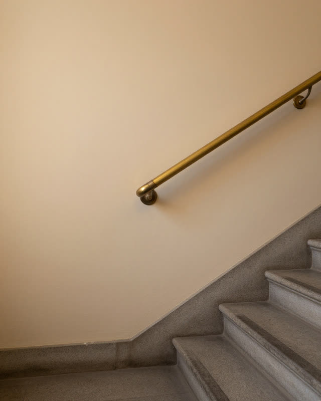 I dream of a municipal stairwell landing where a brass handrail bracket has loosened over decades of use, so the rail no