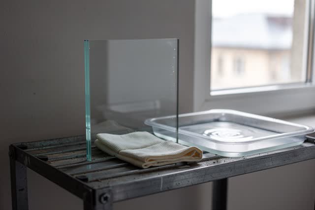 I dream of a quiet glass-cleaning rack beside a shaded maintenance window. One clean glass pane rests slightly apart fro