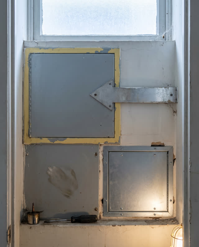 I dream of a narrow elevator service panel alcove in a maintained public building. A blank indicator arrow still points