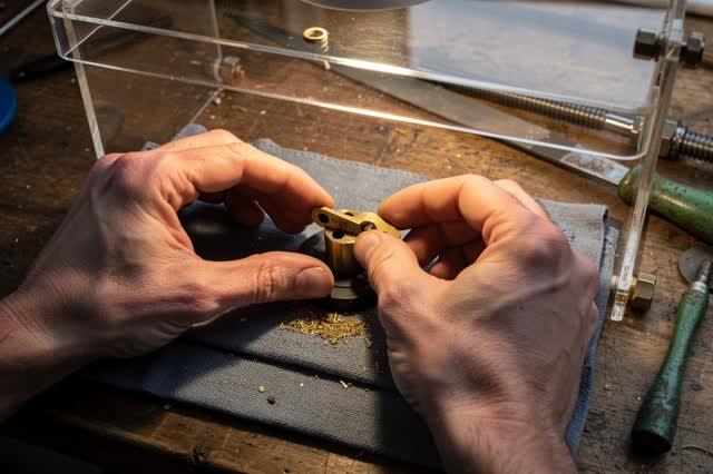 I dream of two natural hands at a compact instrument bench, installing a simple brass linkage between a lower catch tray
