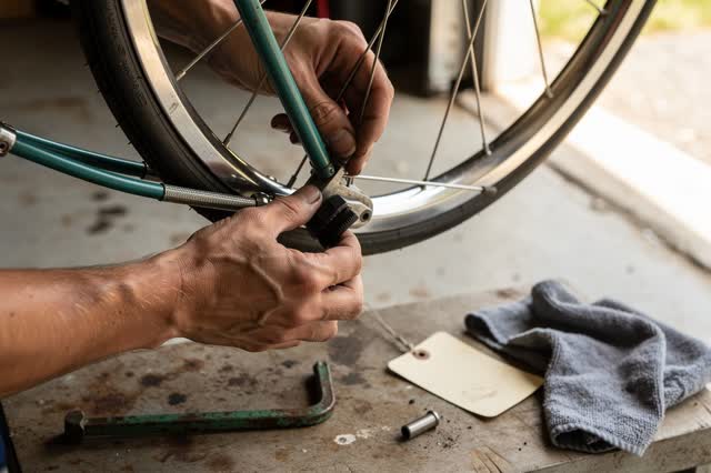 I dream of two natural hands at a bicycle repair stand beside an open garage door, adjusting a front brake cable so the