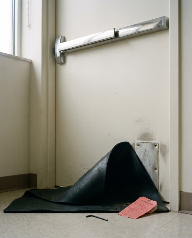 I dream of a fire-escape door mockup in a plain safety training room, where the bright push bar still wins the eye. A po