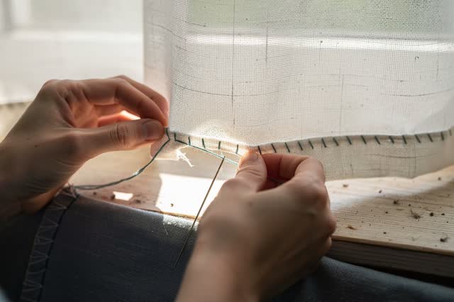 I dream of two natural hands mending a plain curtain hem exactly where light escapes. A narrow line of side daylight glo
