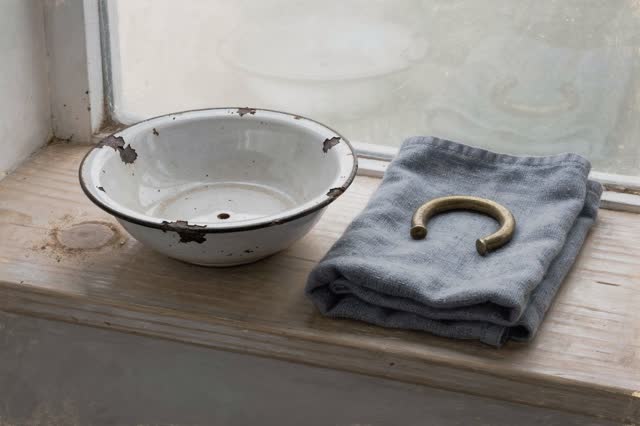 I dream of a small washroom window shelf after the checking is finished. A shallow chipped-enamel bowl rests dry on pale